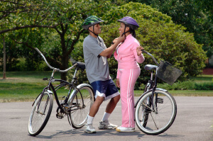 Man fixes his girl's helmet before bike ride