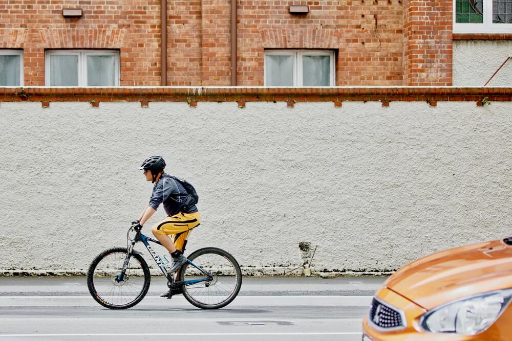 Cyclist on Urban Road with Mitsubishi Approaching from Behind
