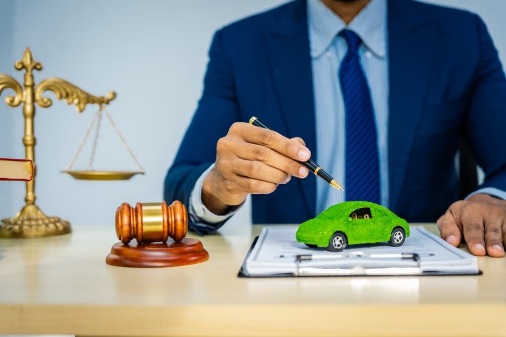 A male lawyer in a formal suit works diligently at his desk, reviewing contracts and addressing legal matters, while maintaining a strong commitment to sustainability and eco-friendly practices.