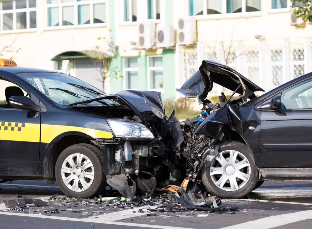 The image showing a car collision at a city road intersection, including an Uber vehicle.