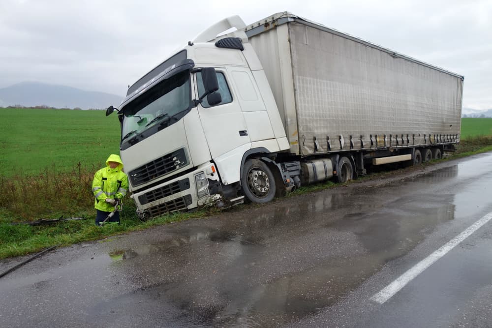 A truck ended up in a ditch following a road accident on a rainy autumn day. Rescuers arrived at the scene to assist with the situation.